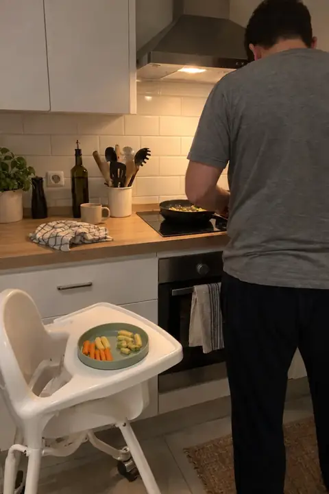 Cocina pequeña con la trona junto a la encimera y una sartén al fuego